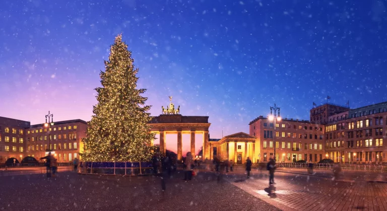 Brandenburger Tor i Berlin med juletræ og faldende sne om aftenen